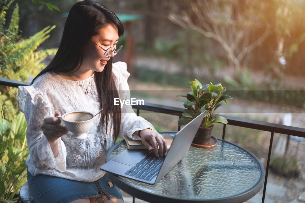 WOMAN USING PHONE WHILE SITTING AT TABLE