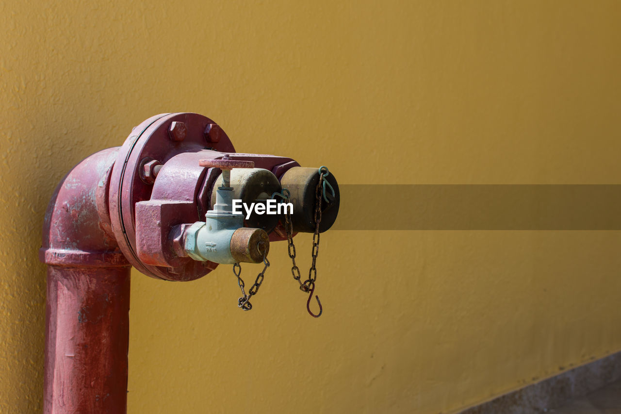 Close-up of fire hydrant against wall