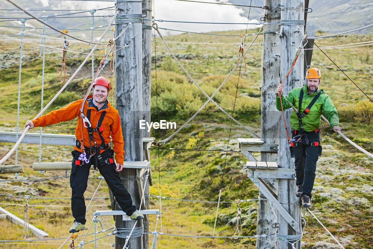 Two men balancing on high rope obstacle course in iceland