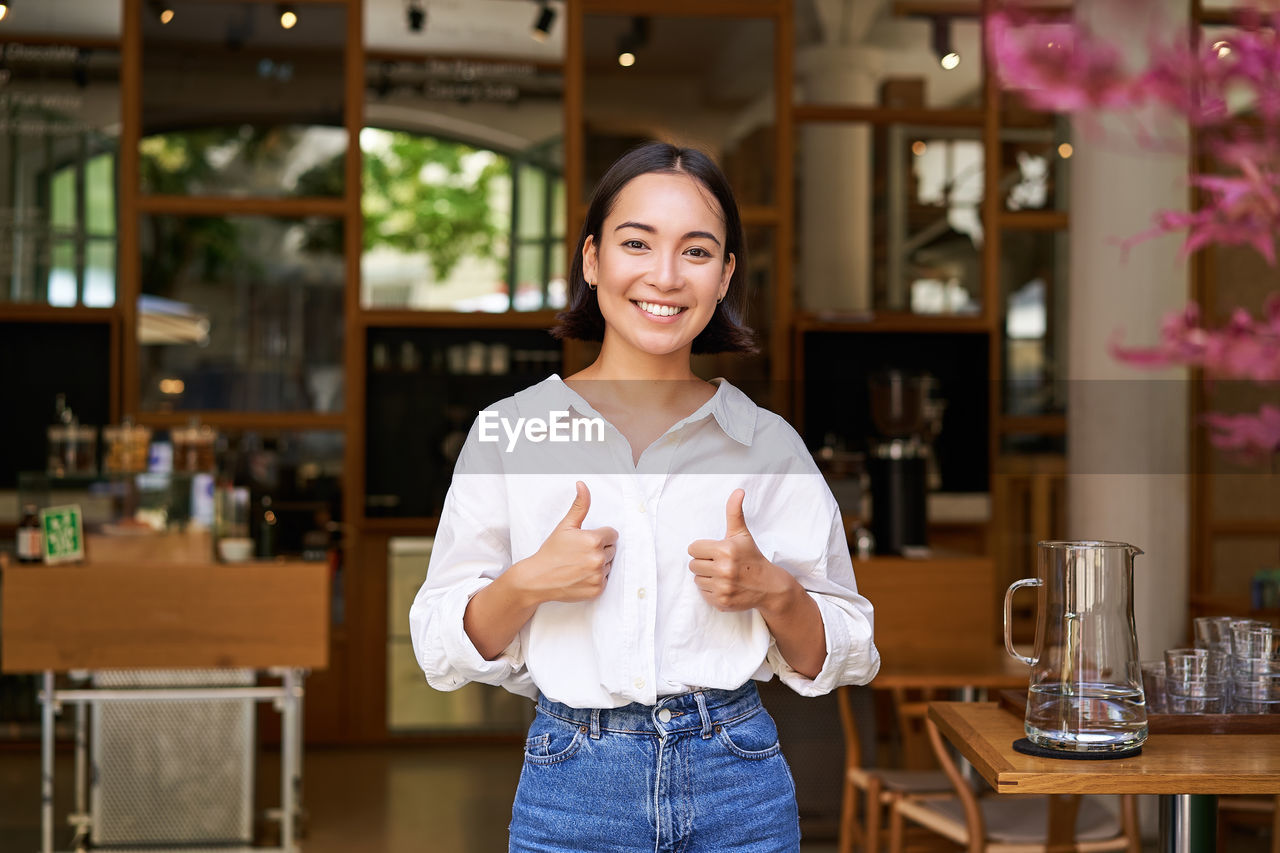 portrait of smiling young woman standing at cafe