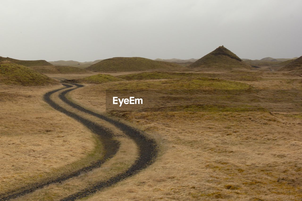 Scenic view of road by mountains against sky