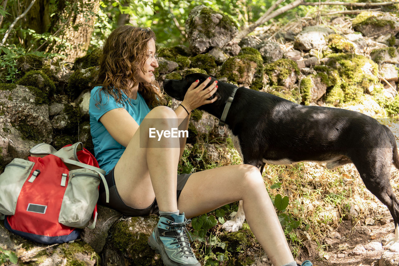 Woman relaxing and resting on a mountain trail with her dog.