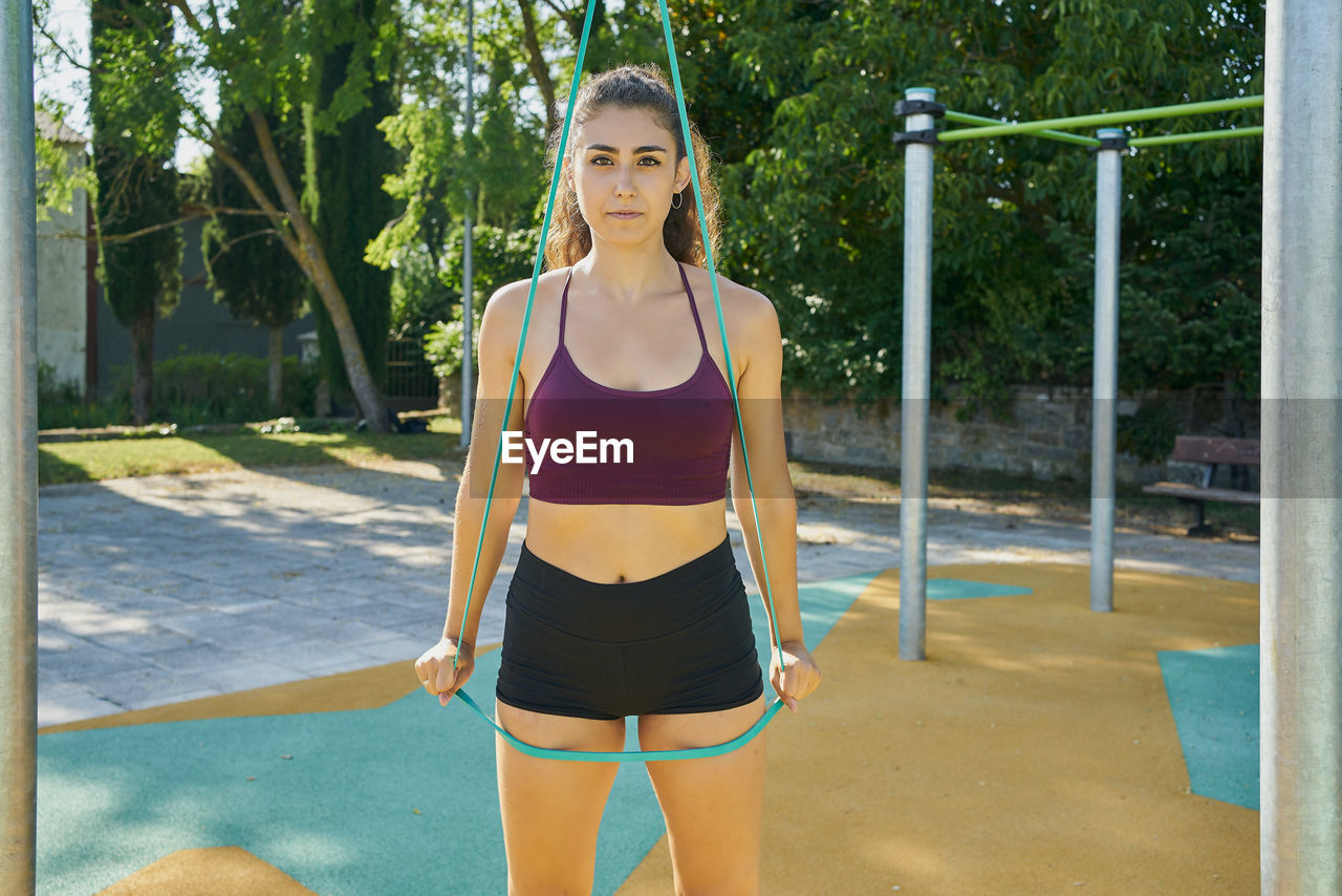 Front view of a young woman practicing calisthenic with elastic band