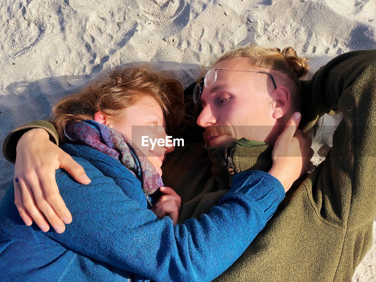 Side view of young couple lying at beach