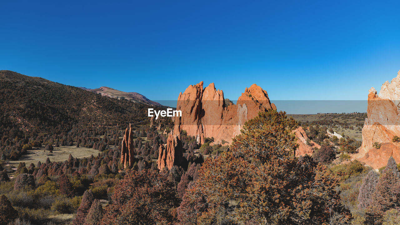 Panoramic view of rocks and trees against blue sky