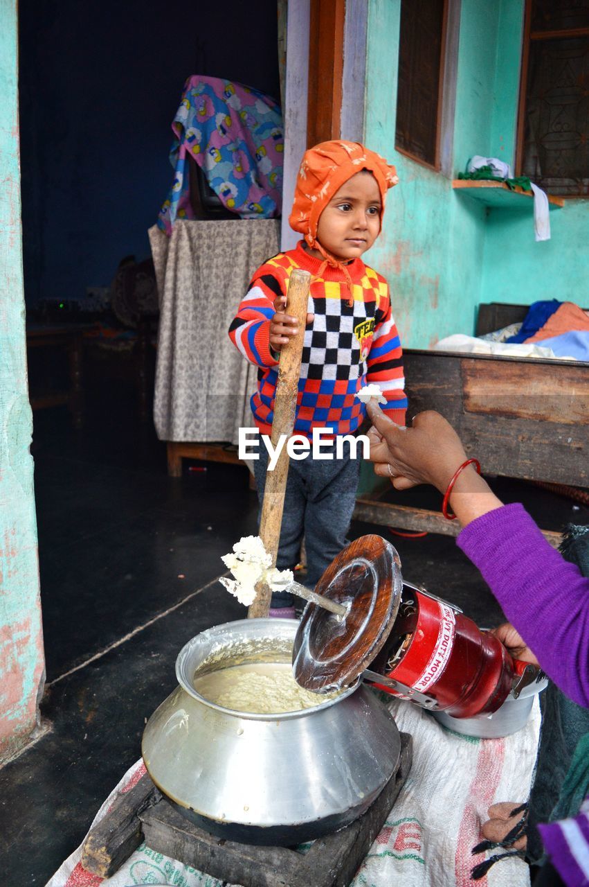 Woman preparing dairy product while feeding son at home