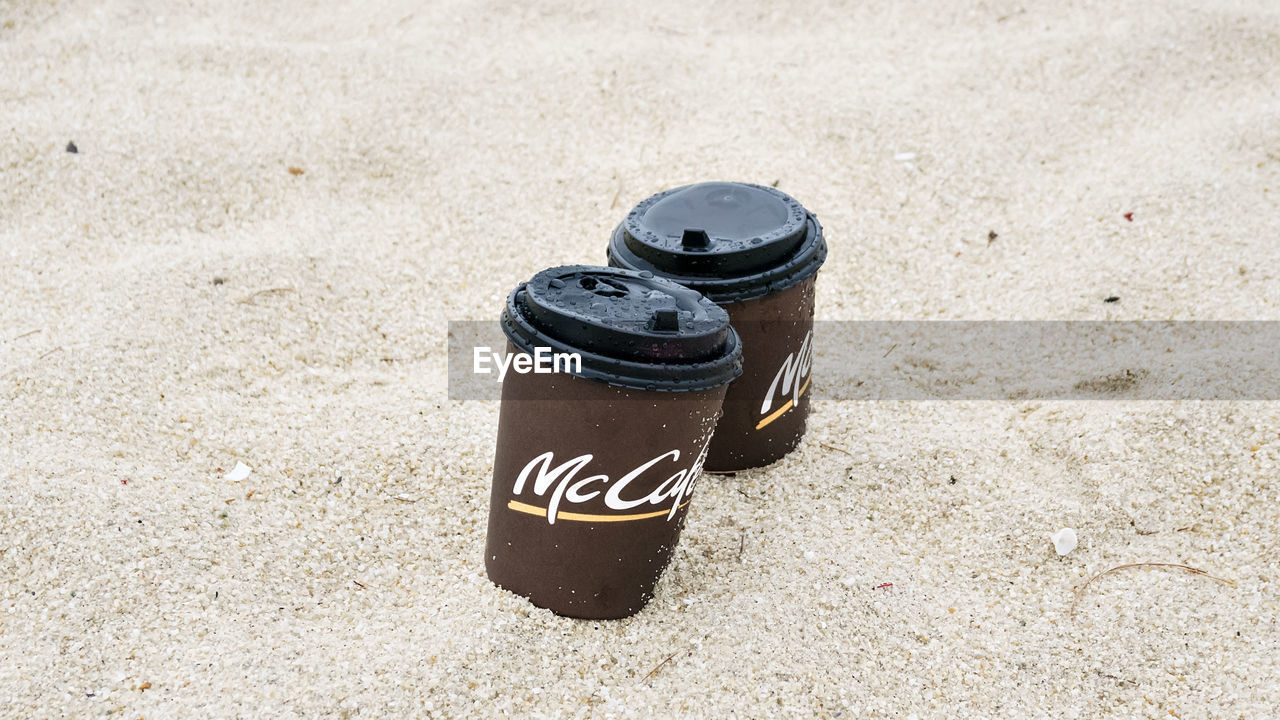 HIGH ANGLE VIEW OF METALLIC CONTAINER ON SAND