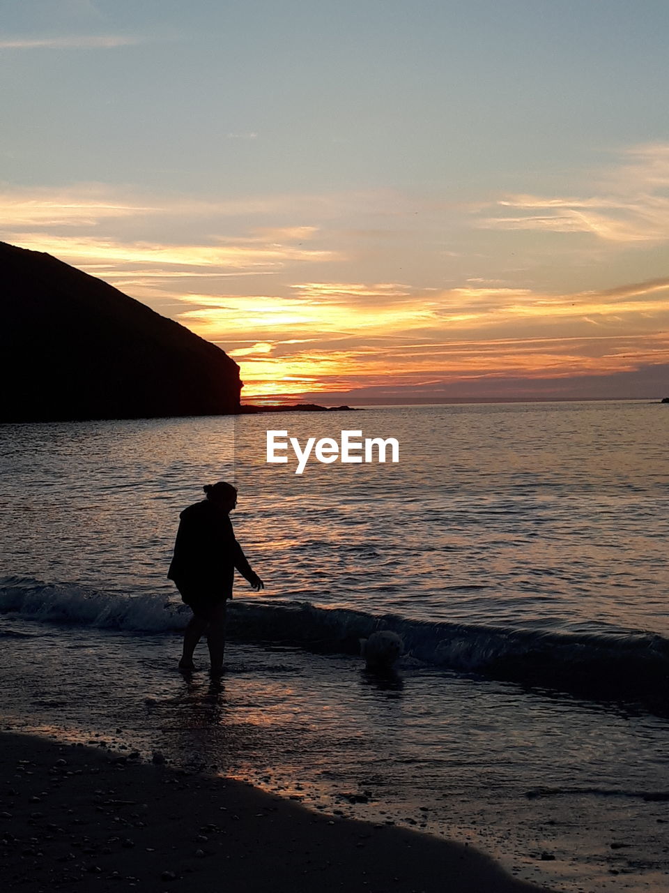 REAR VIEW OF SILHOUETTE WOMAN WALKING ON BEACH AGAINST SKY