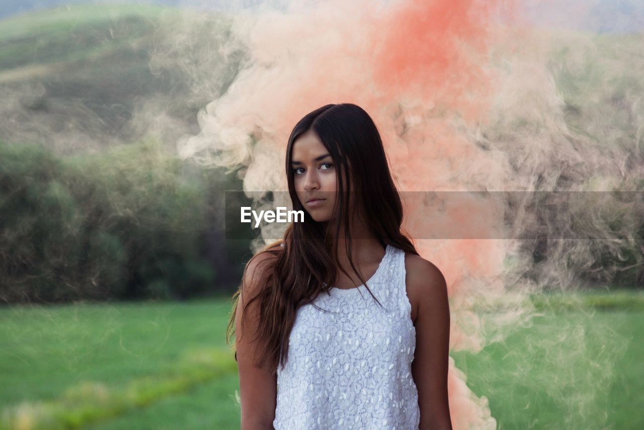 Young woman surrounded by pink smoke