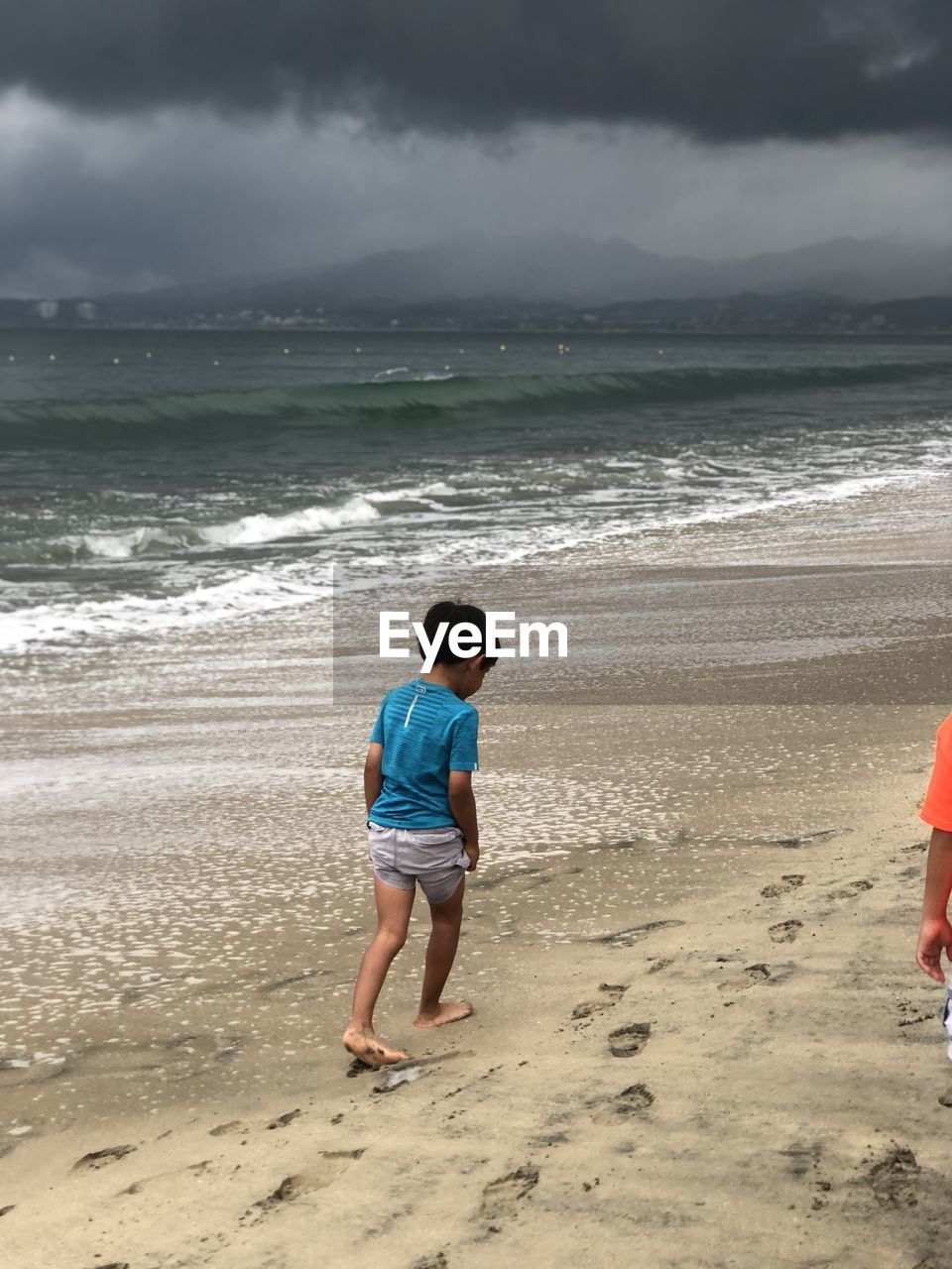 REAR VIEW OF BOYS ON BEACH