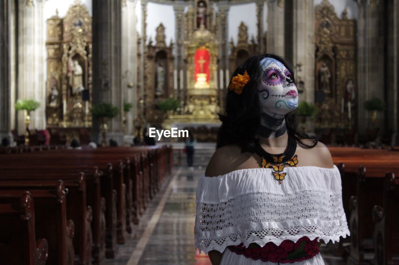 Young woman with painted face standing in church