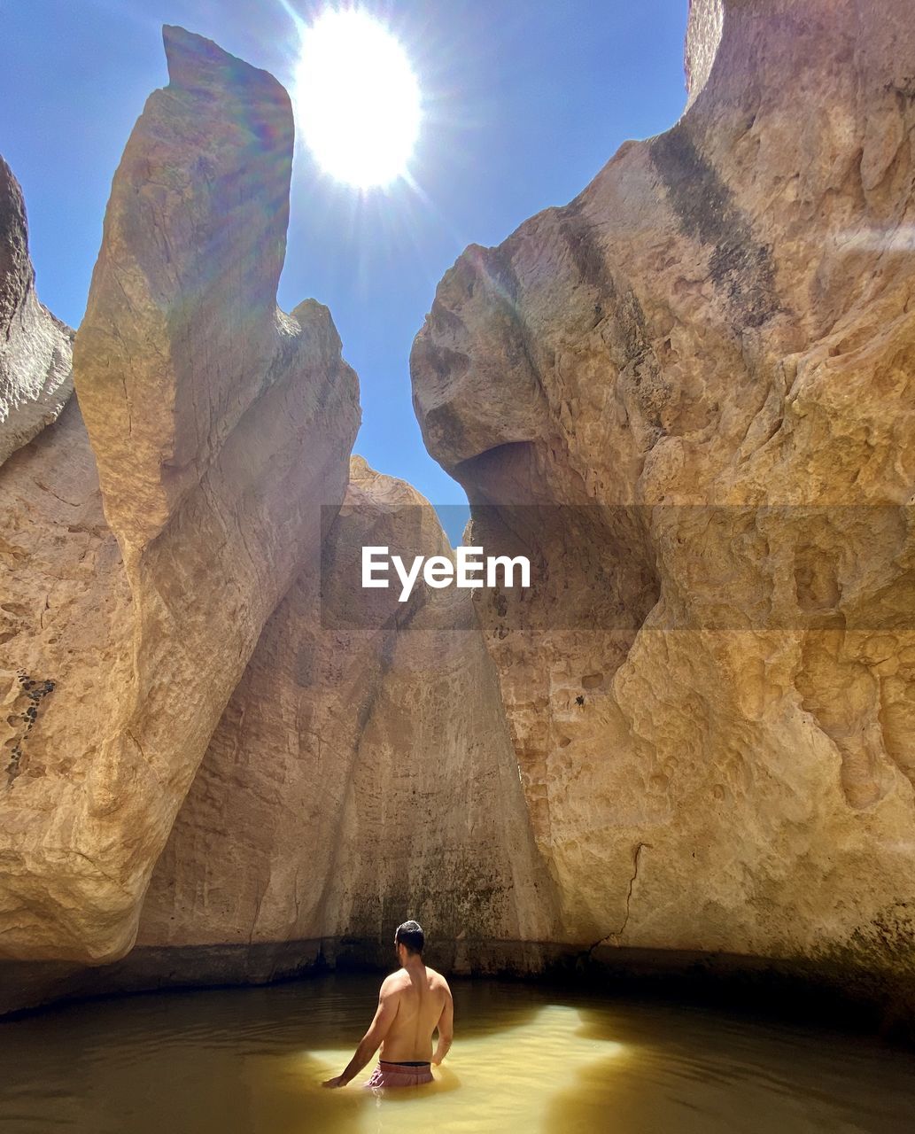 REAR VIEW OF WOMAN WALKING ON ROCKS