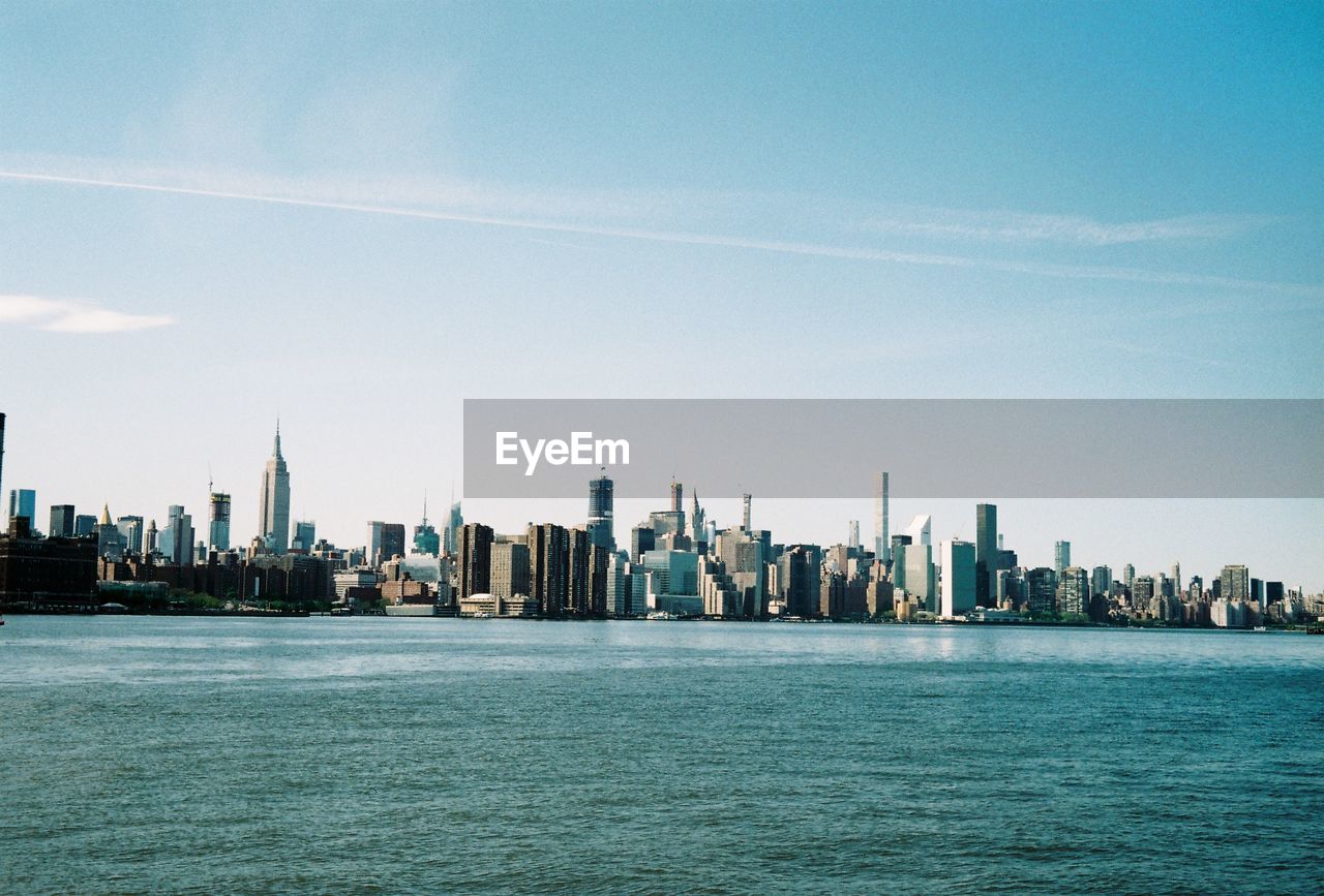 Sea and buildings in the city of new york city against the sky