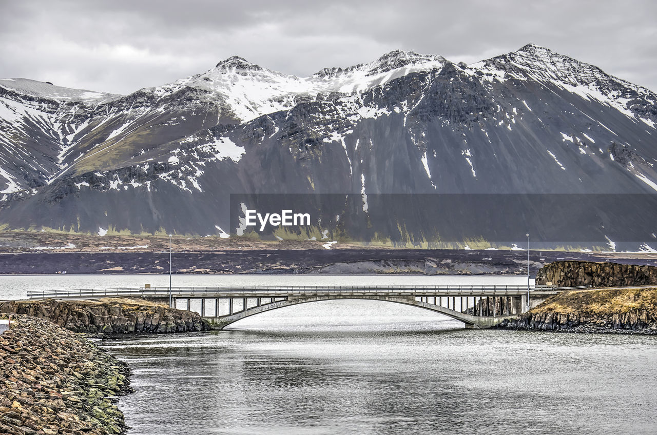Bridge over snowcapped mountains against sky