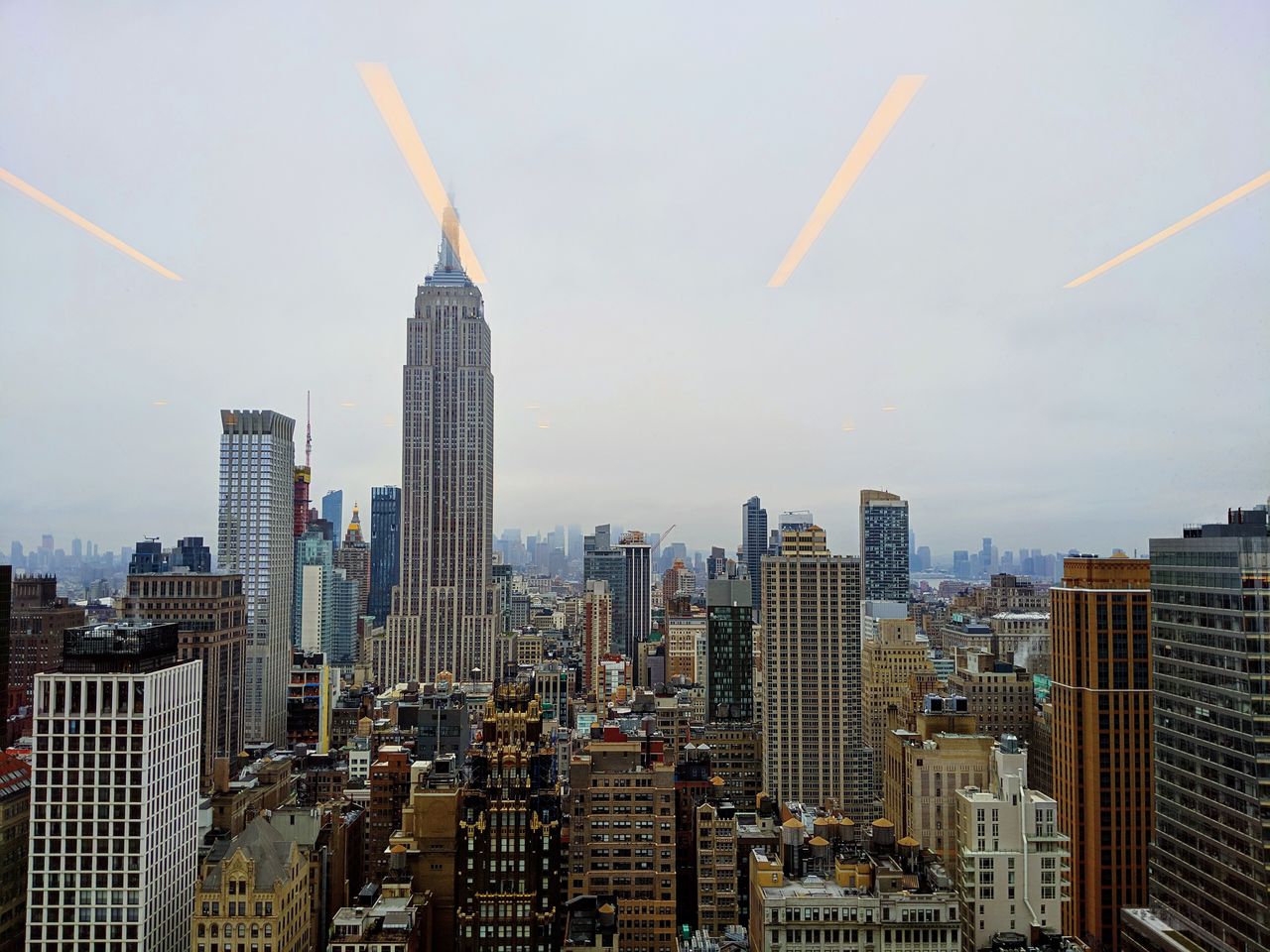 Empire state building and towers in city against sky