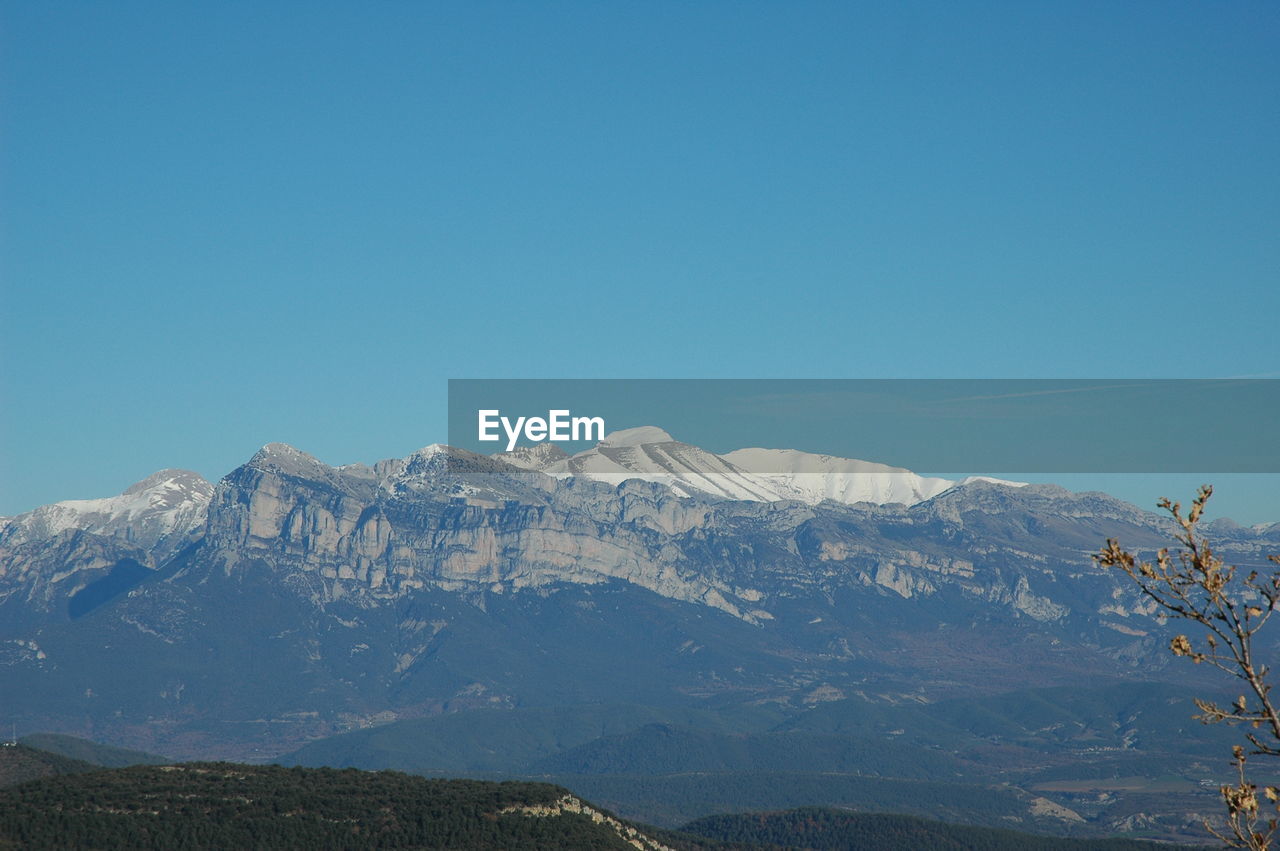 Scenic view of snowcapped mountains against clear blue sky