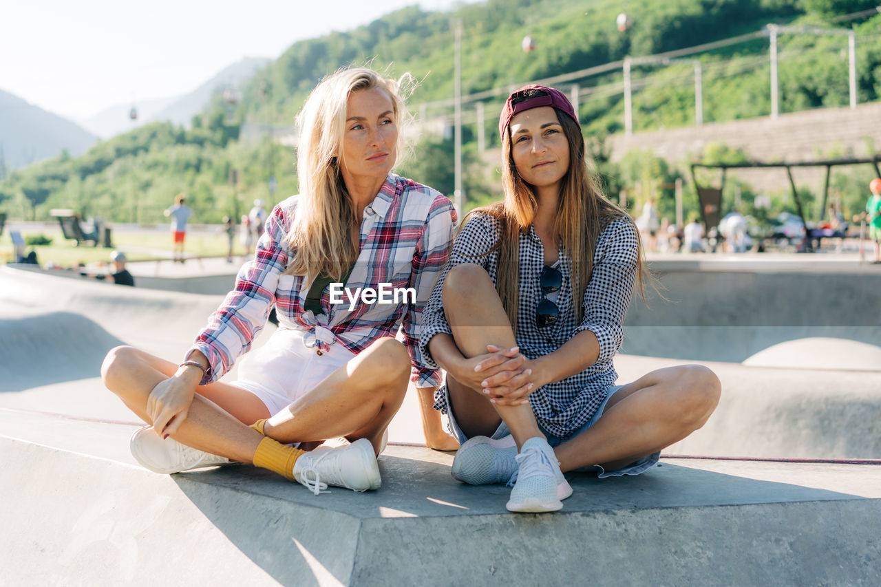 Portrait of two female friends sitting in a skatepark.