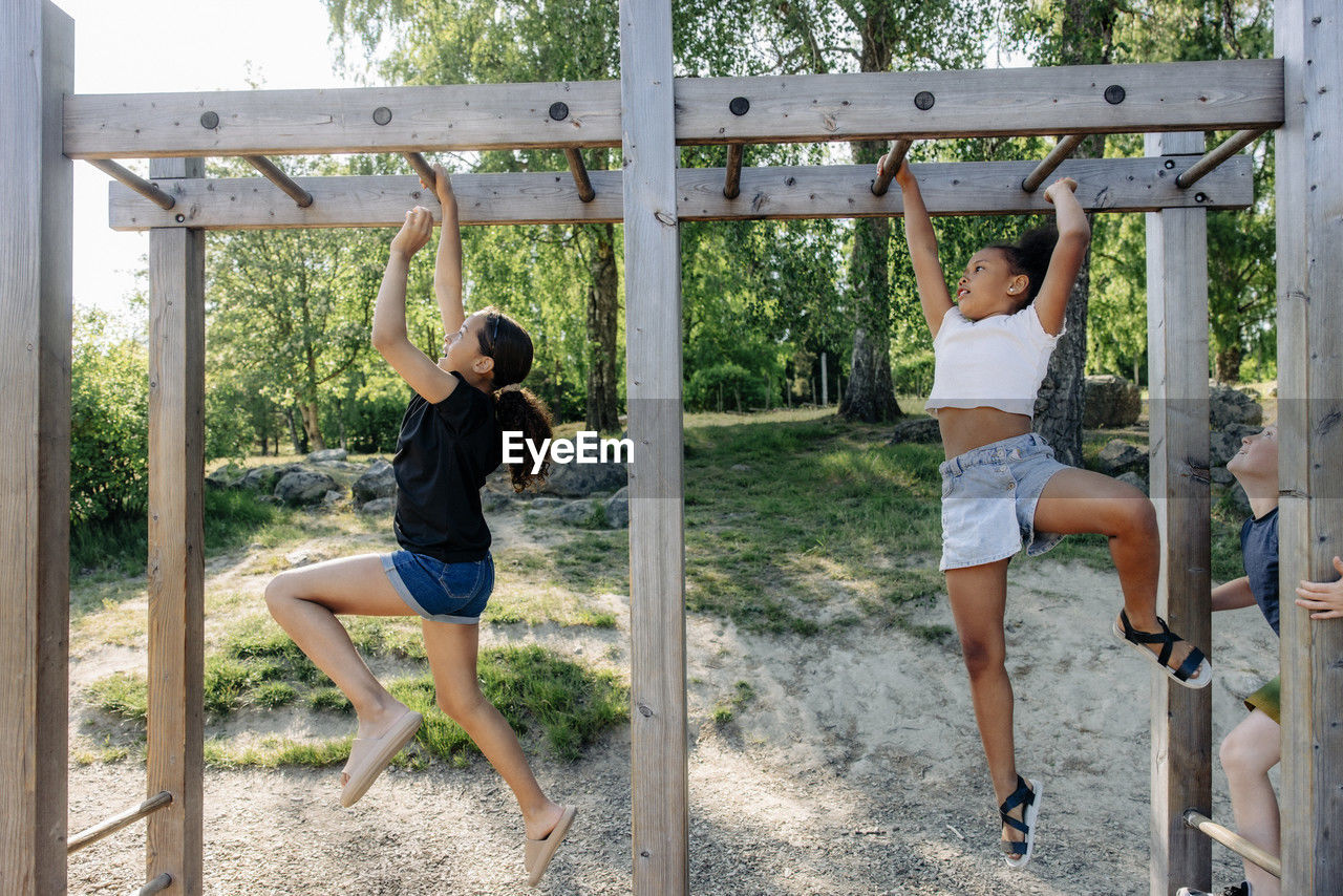 Girls practicing monkey bars while playing during summer camp