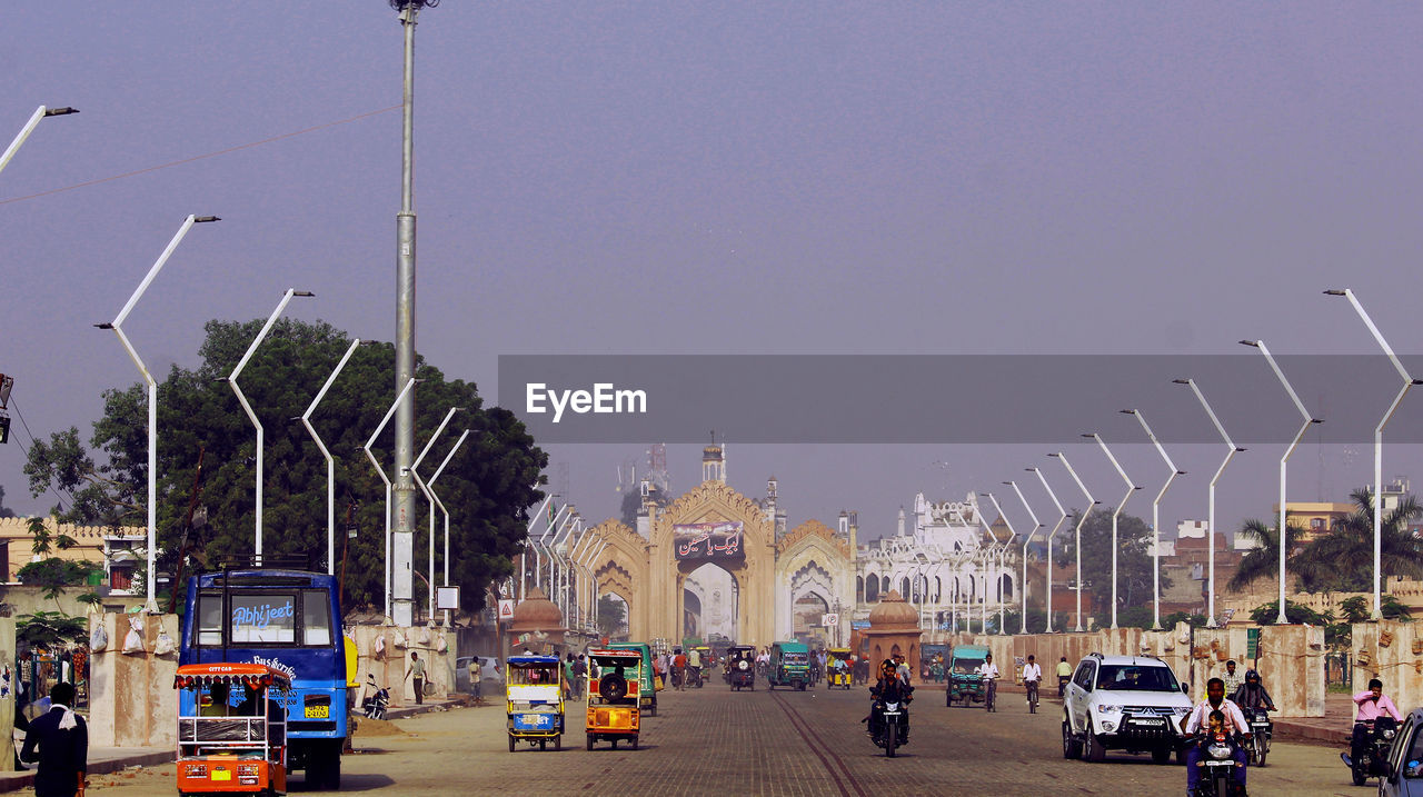 VEHICLES ON ROAD AGAINST SKY IN CITY