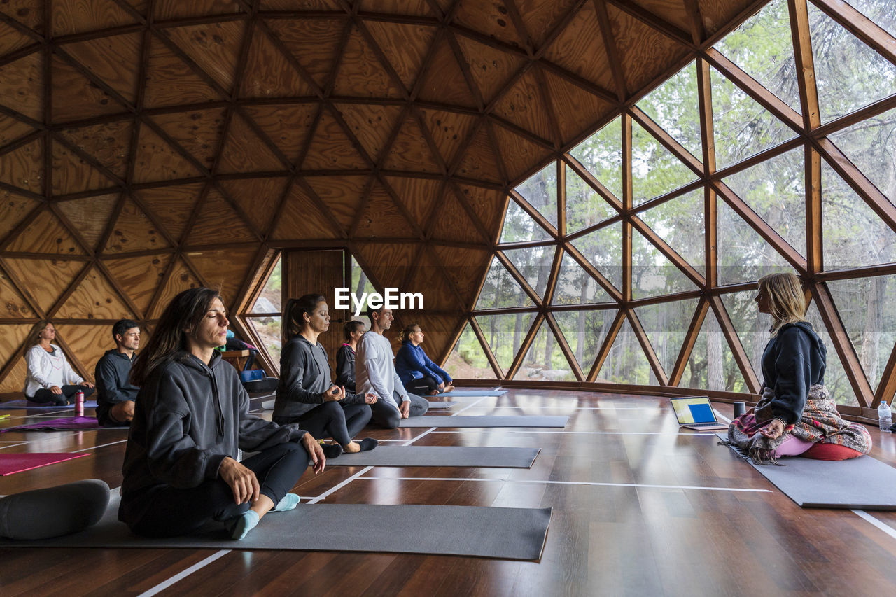 Yoga instructor and tourists practicing breathing exercise at health retreat