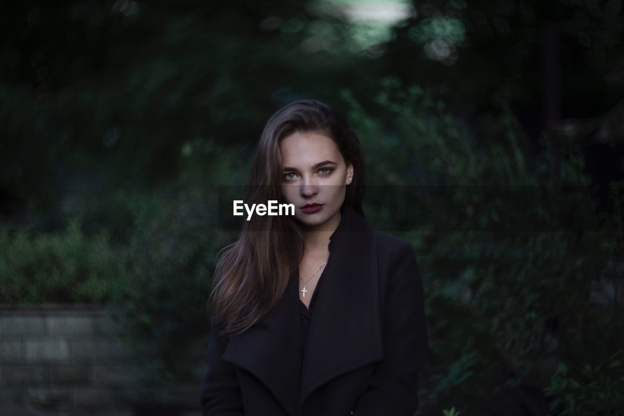 PORTRAIT OF BEAUTIFUL WOMAN STANDING AGAINST TREES