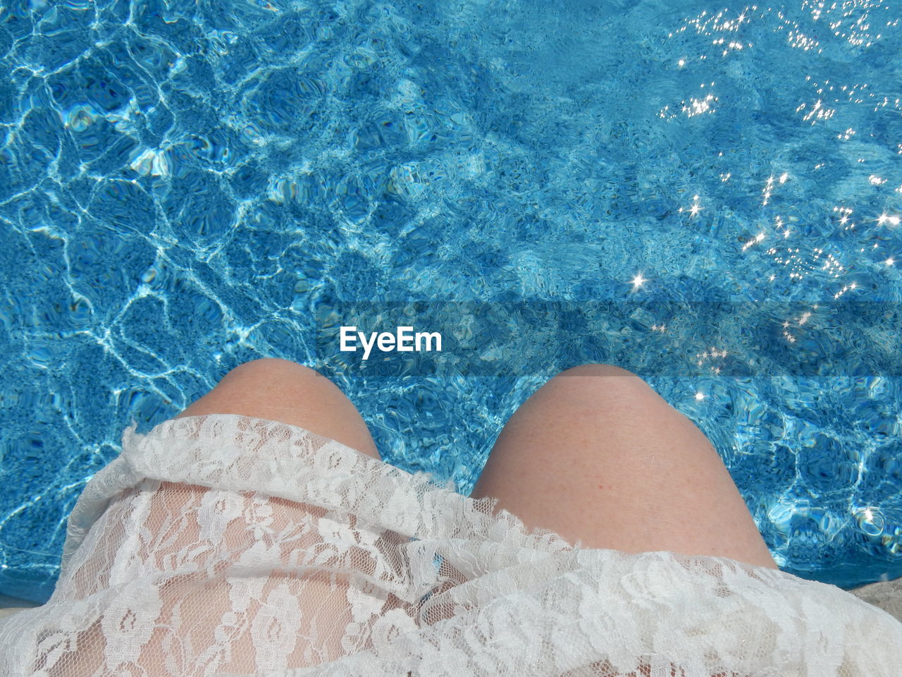 Midsection of woman sitting at poolside