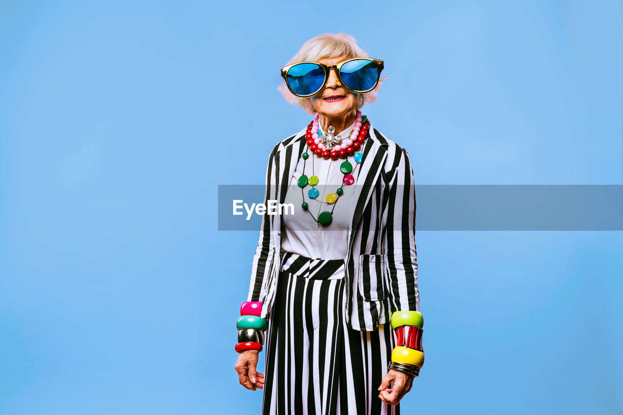 Senior woman wearing sunglasses against blue background