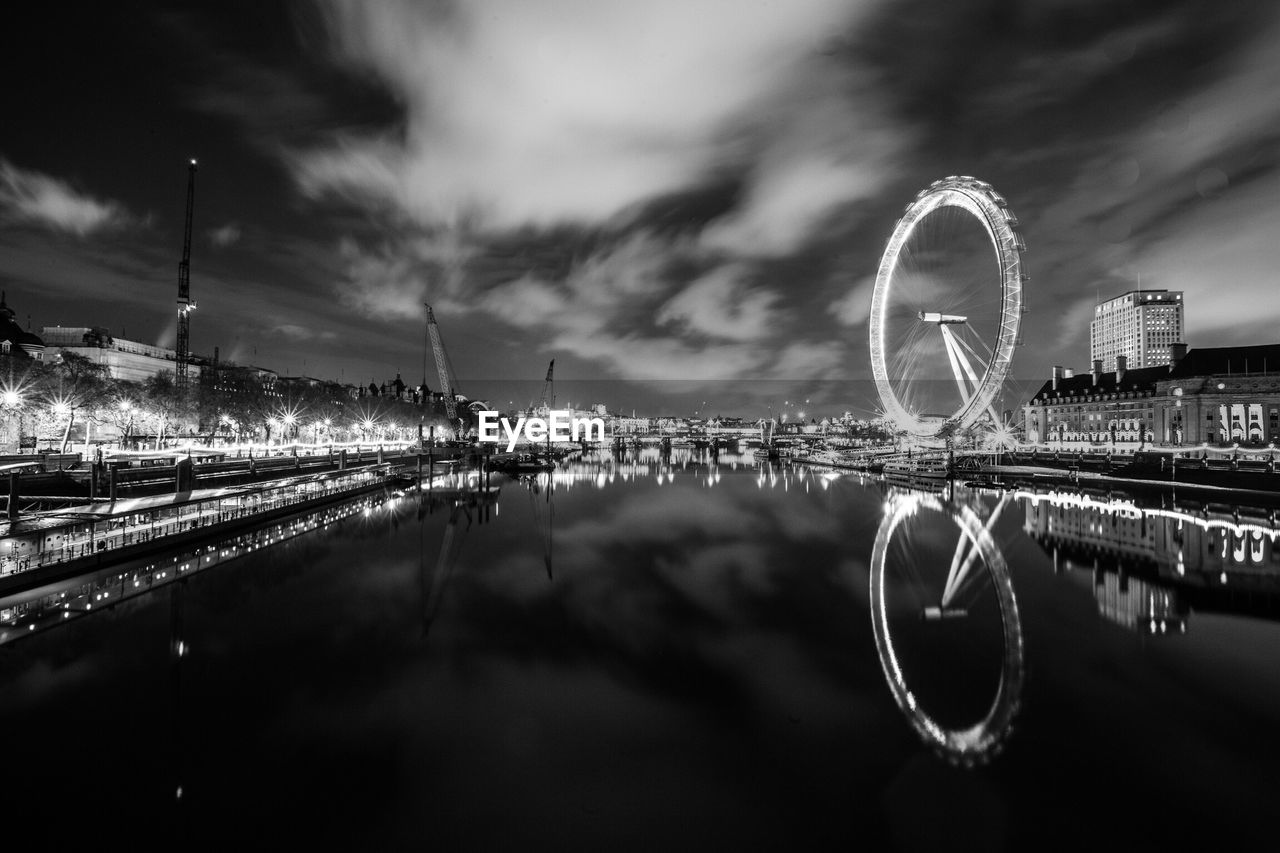 London eye by thames river against sky seen from westminster bridge