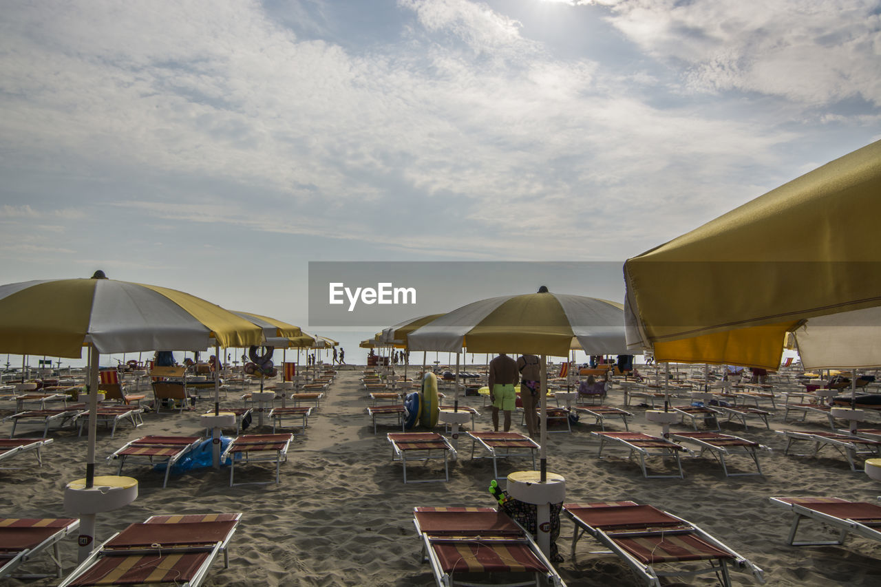 Chairs and parasols at beach against sky