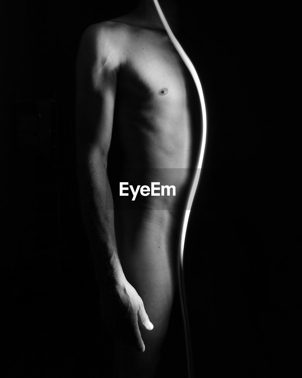 Midsection of naked man standing against black background