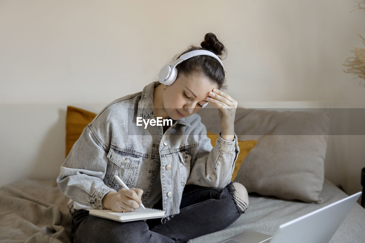 Young beautiful woman with casual clothes sitting on the bed at home with laptop computer 