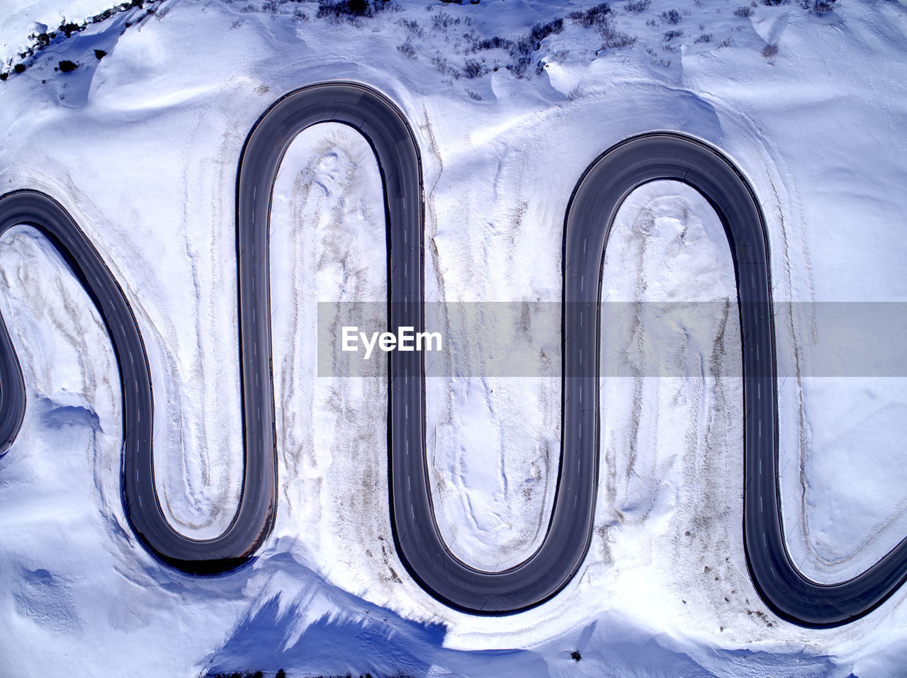 Aerial view of winding road amidst snow covered field during winter