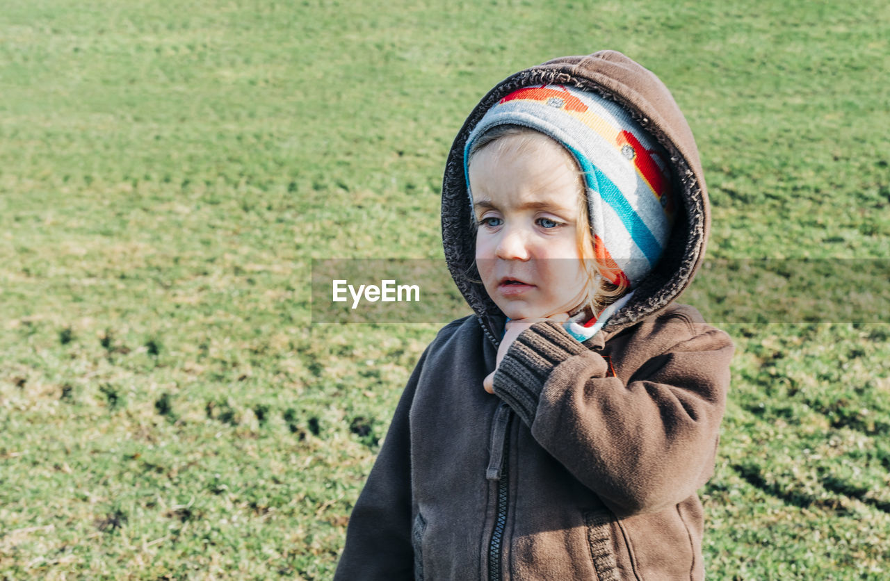 Cute girl wearing warm clothing while looking away on land