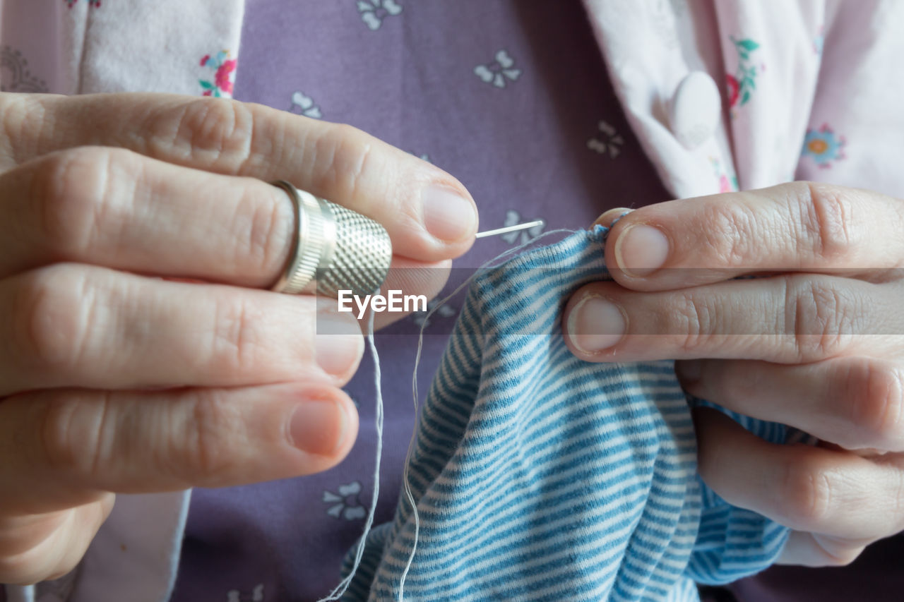 Midsection of woman stitching textile