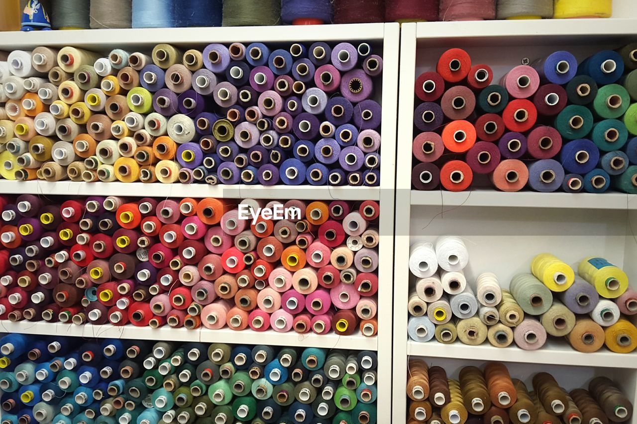 Colorful threads arranged on shelf at store for sale