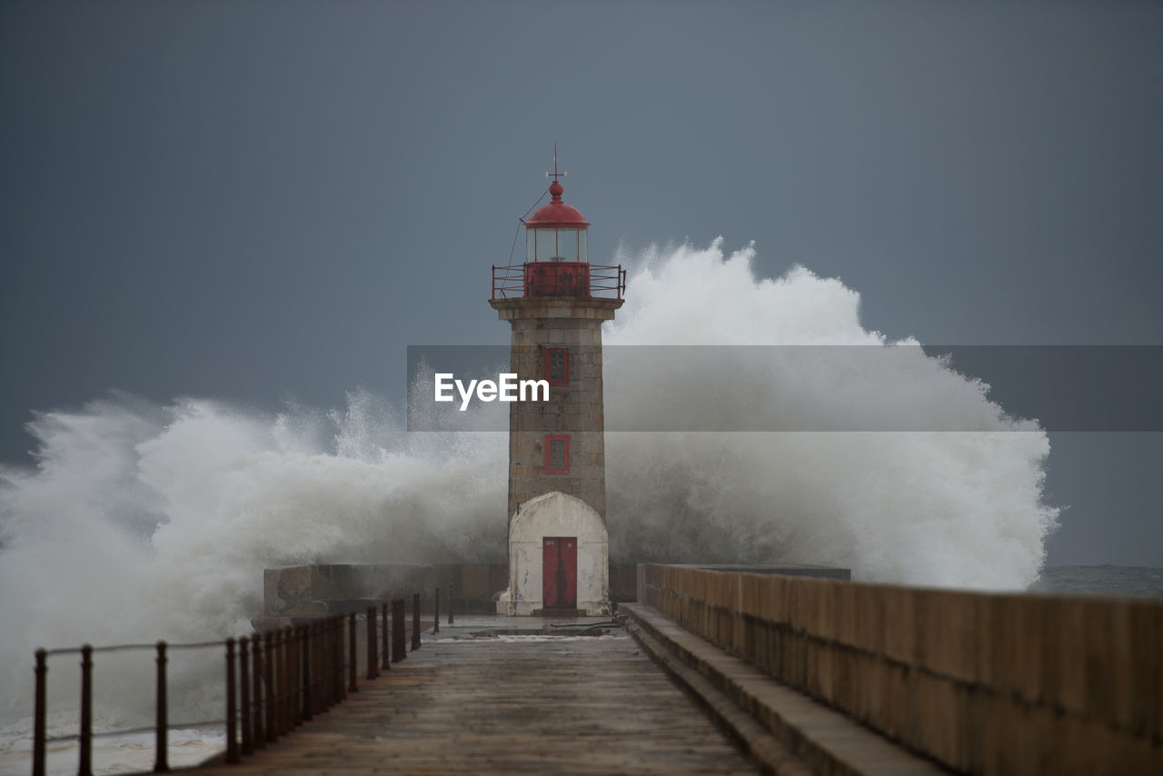 Lighthouse by sea against sky