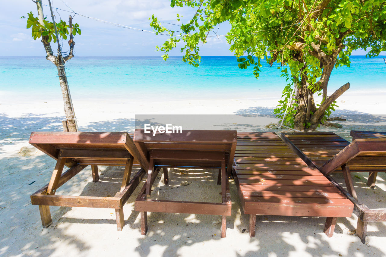 EMPTY CHAIRS AND TABLES BY SWIMMING POOL