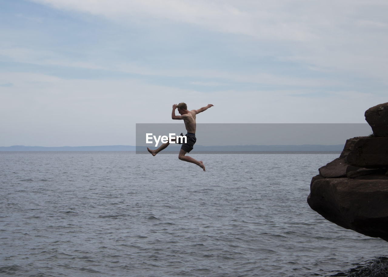 Full length of man jumping in sea against sky