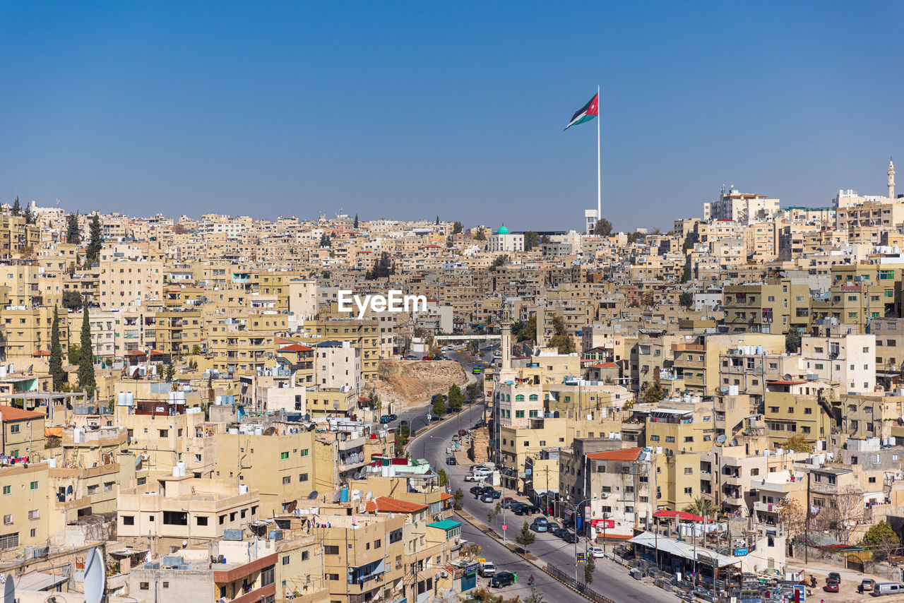 Jordan flag in amman, cityscape view