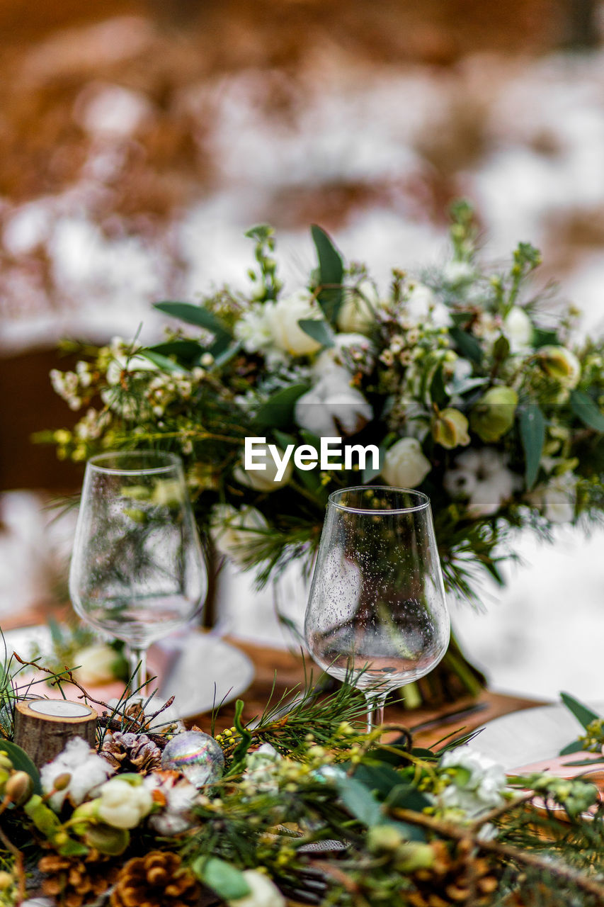 Wedding old wooden table with a flower-filled decoration and placement with glasses at a wedding ceremony in winter on snow in the middle of a forest covered with fresh snow...