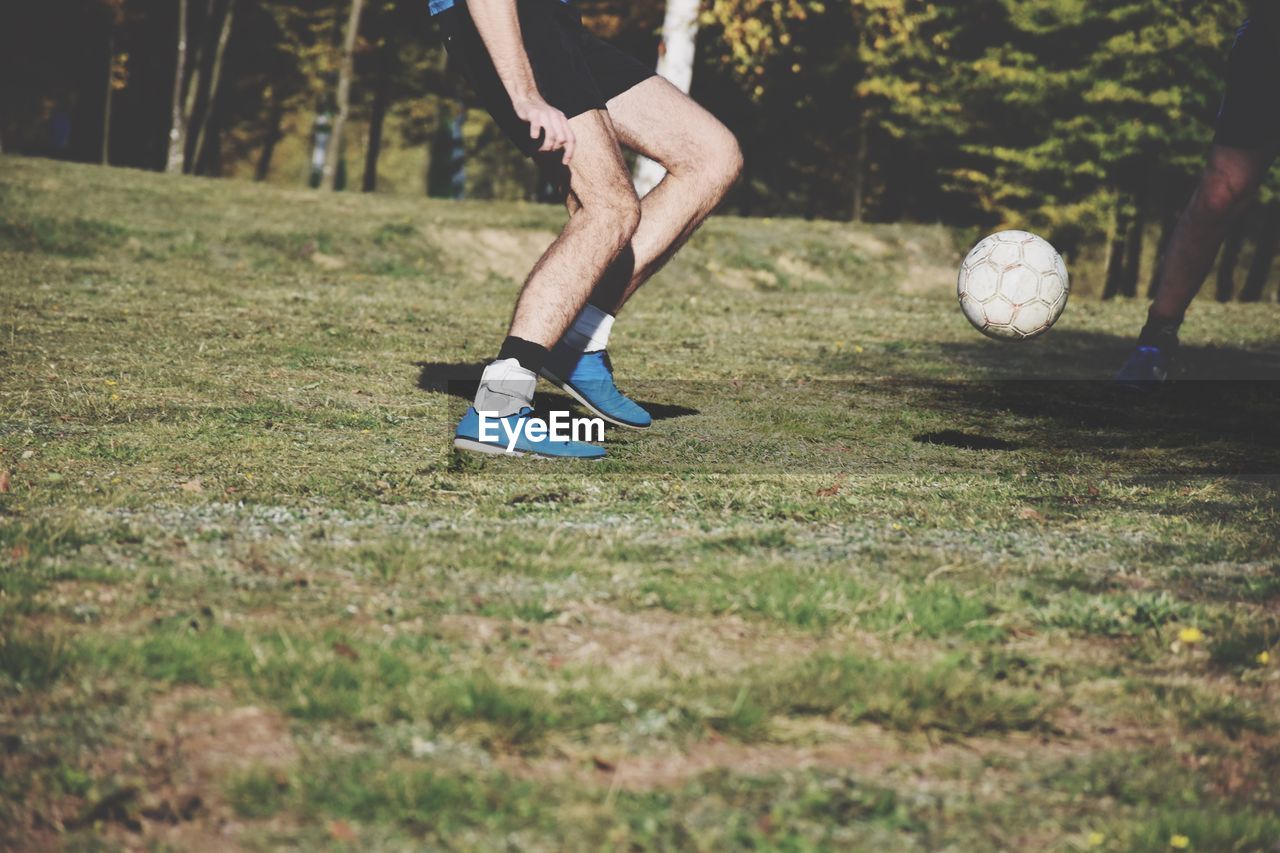 Low section of man playing soccer on field