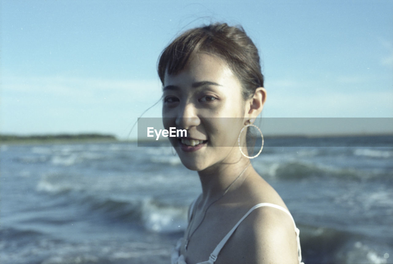 PORTRAIT OF YOUNG WOMAN ON BEACH