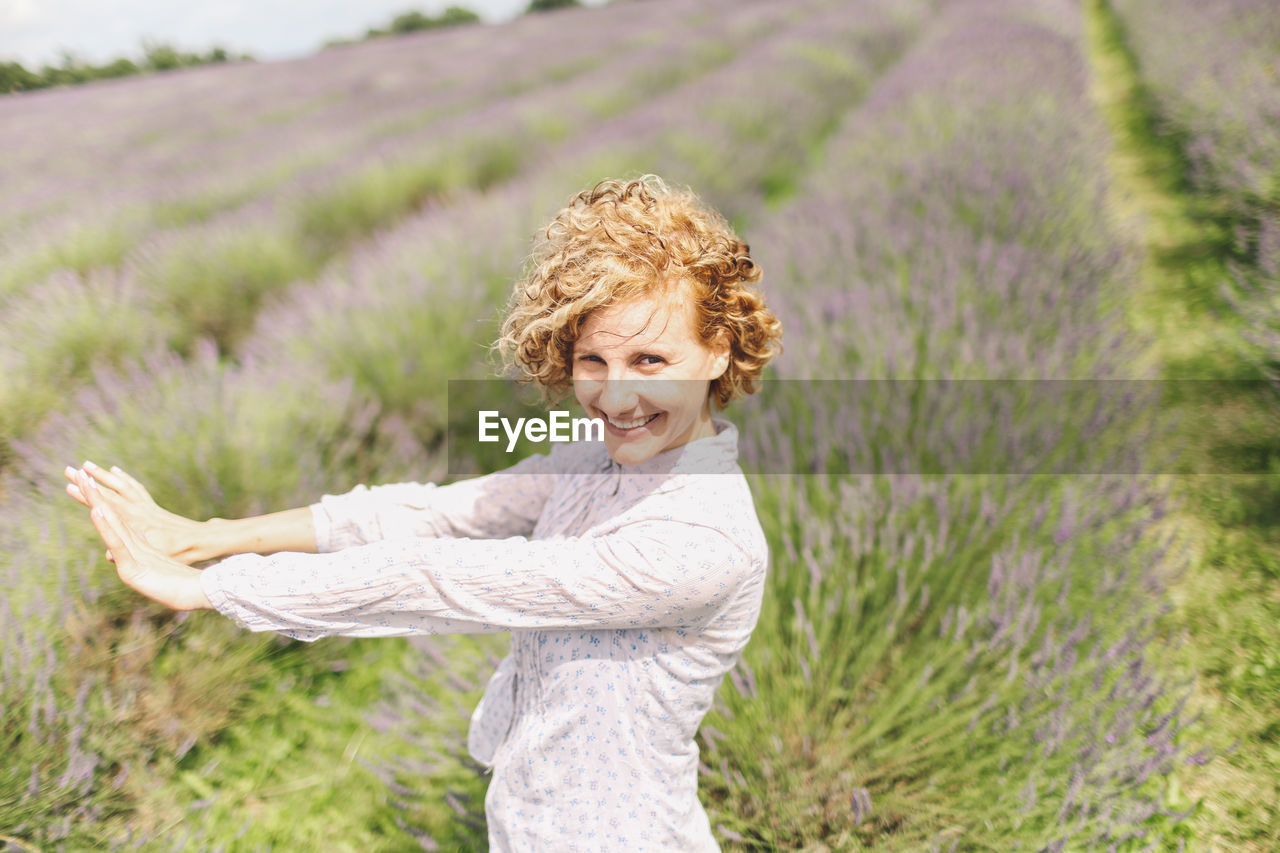 Portrait of happy woman standing on lavender field