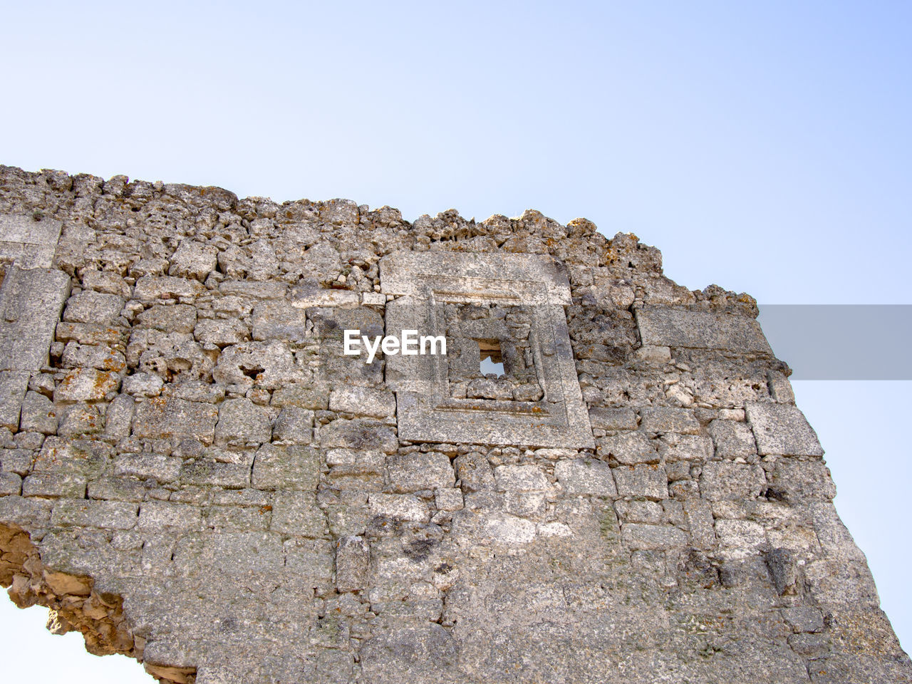 LOW ANGLE VIEW OF STONE WALL AGAINST CLEAR BLUE SKY