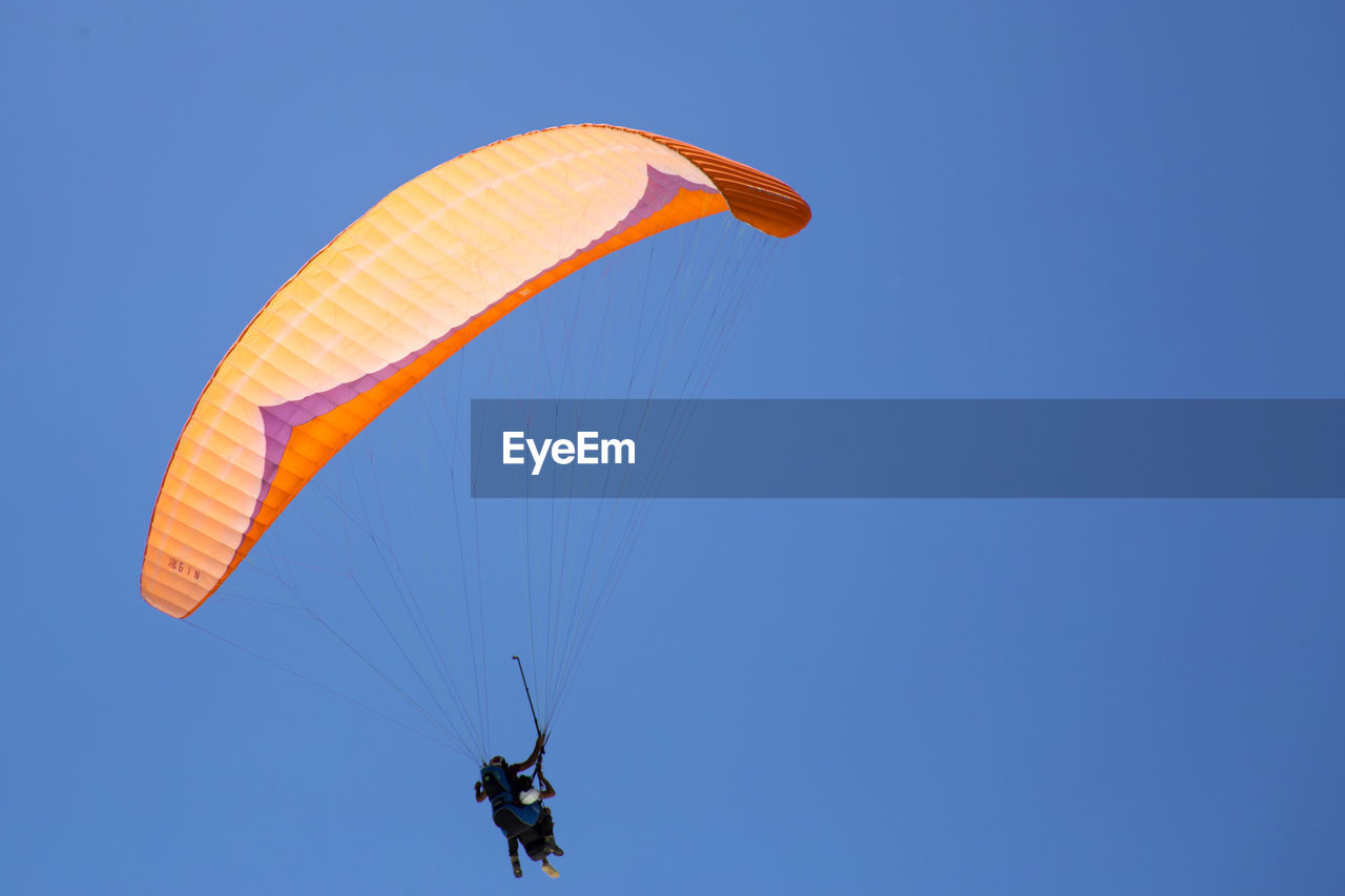 Low angle view of person paragliding against clear blue sky