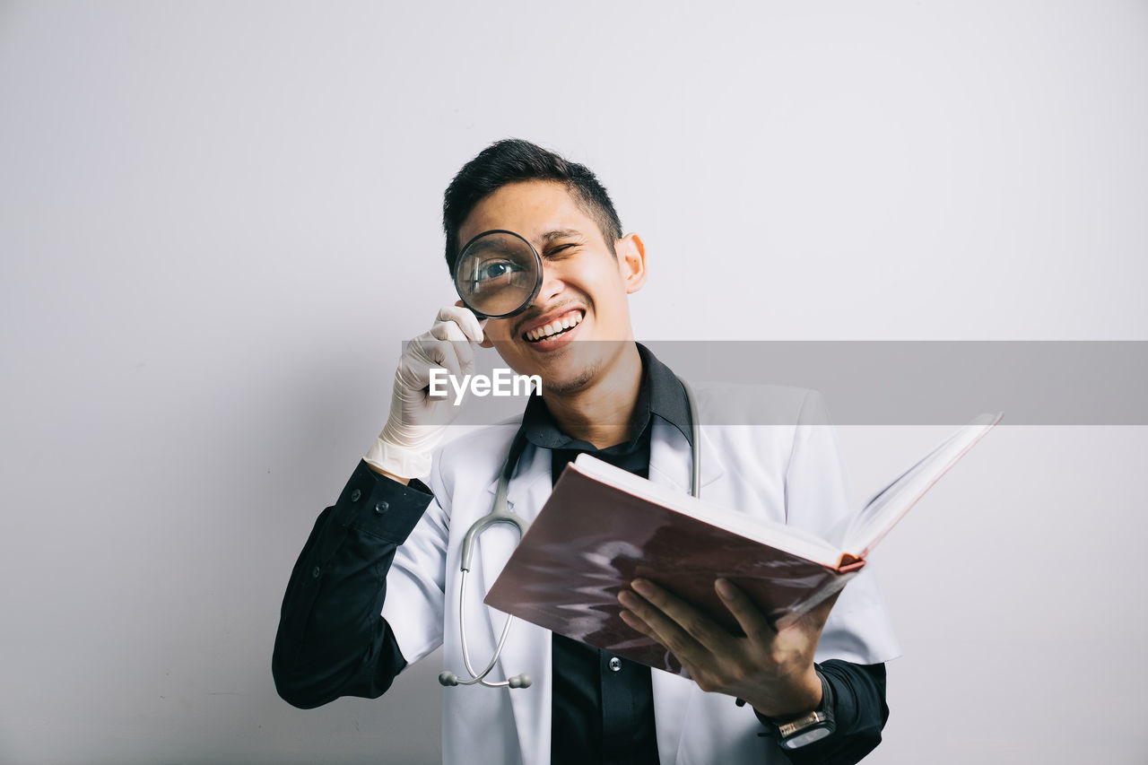 Portrait of scientist magnifying glass over white background