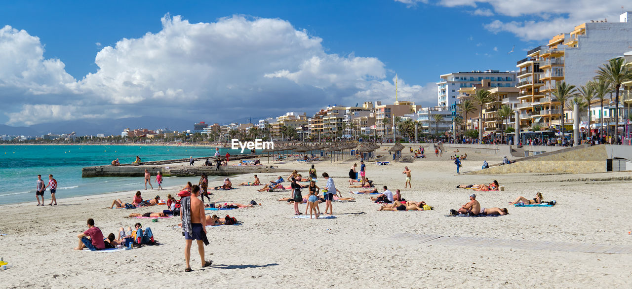 PANORAMIC VIEW OF PEOPLE ON BEACH AGAINST SKY