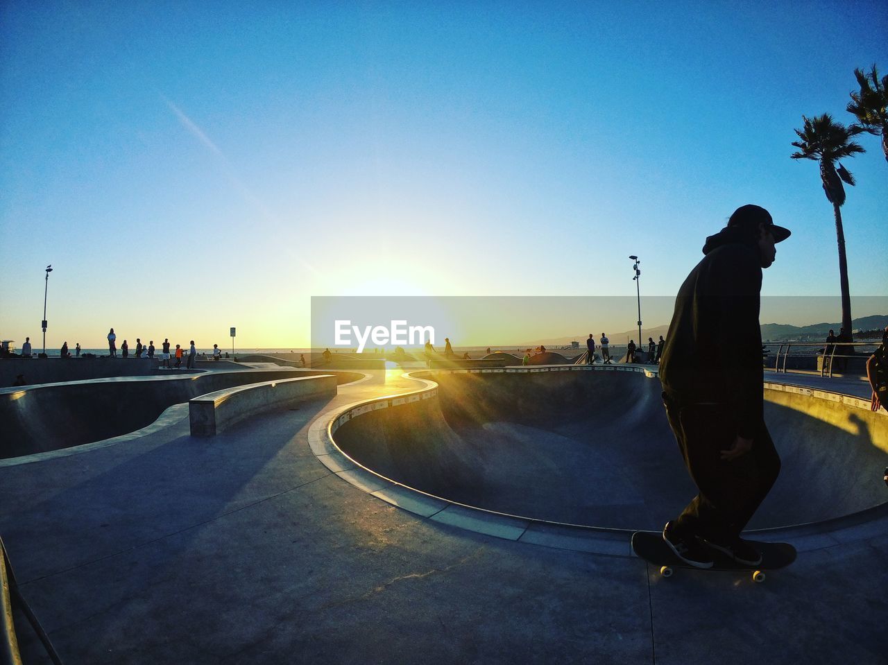 Man skateboarding on road against sky during sunset