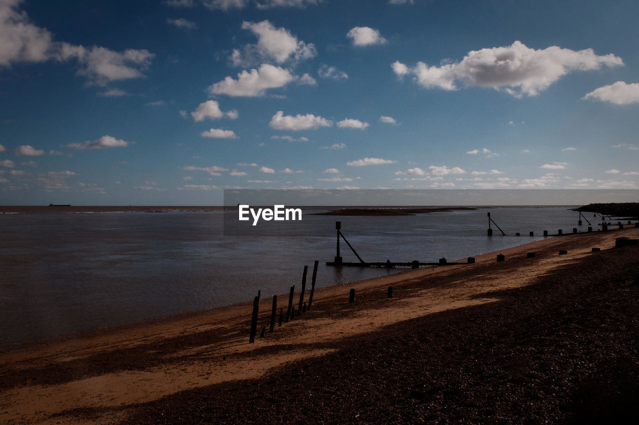 Empty beach against cloudy sky