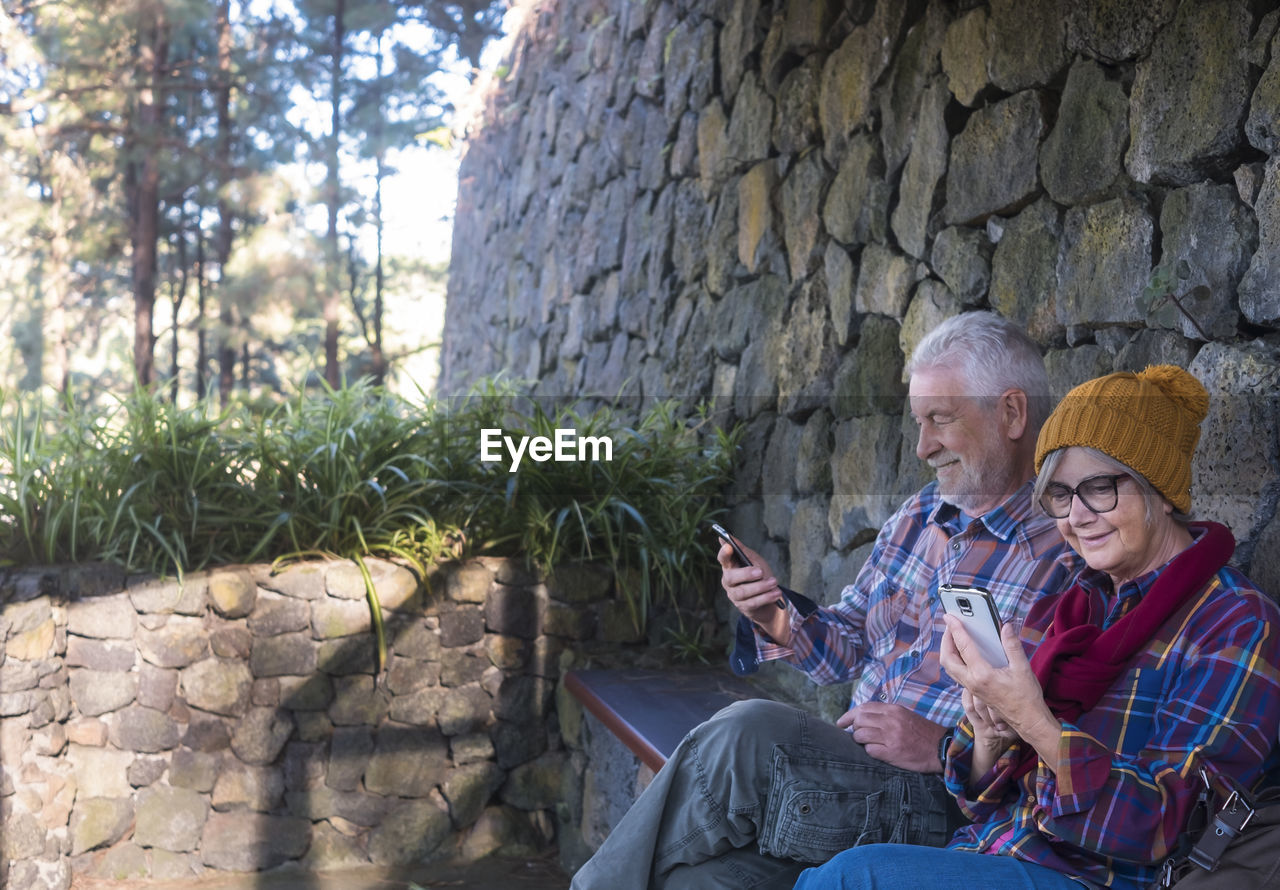 Senior couple using phones while sitting outdoors